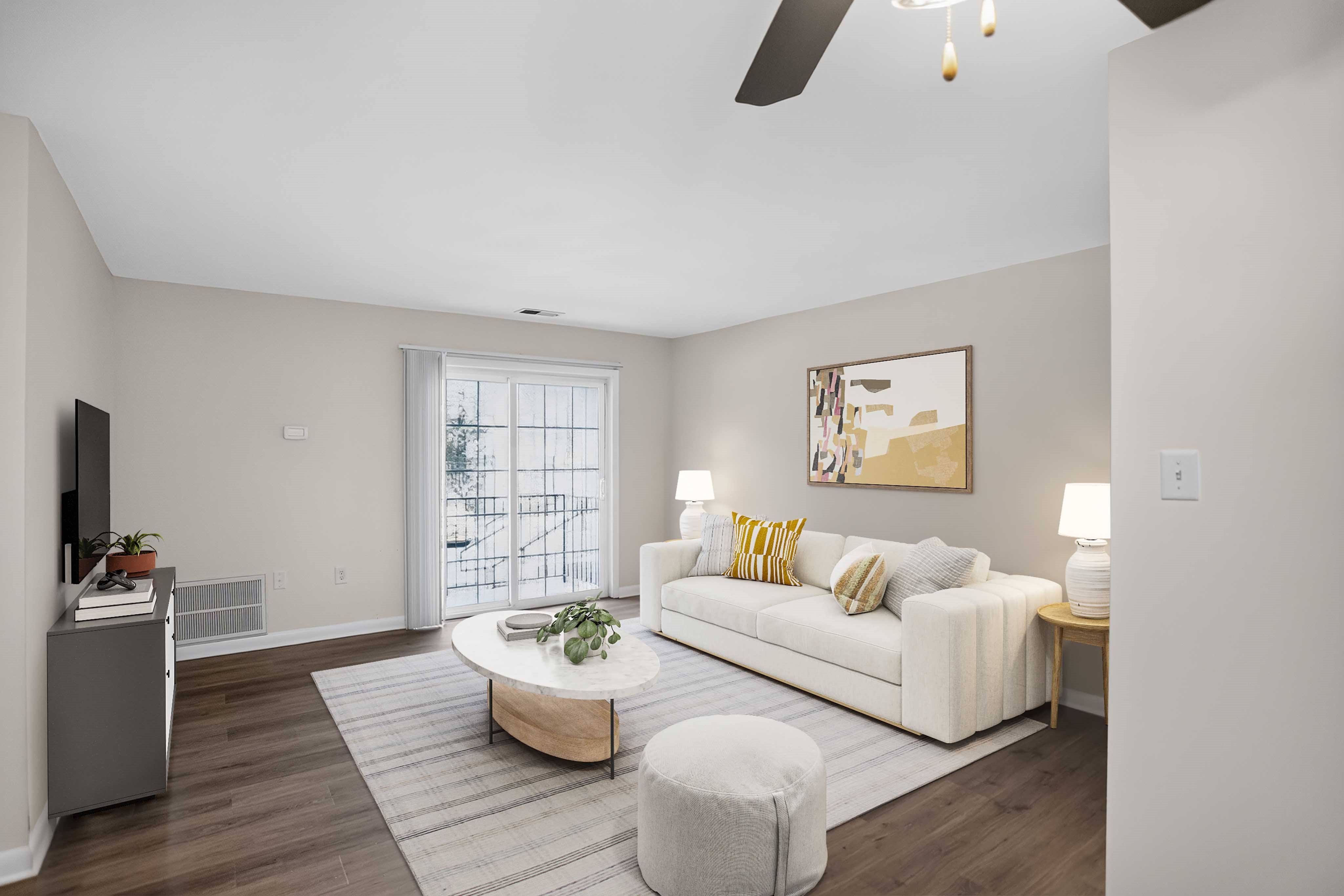 A living room with a white couch, a coffee table, and a ceiling fan.